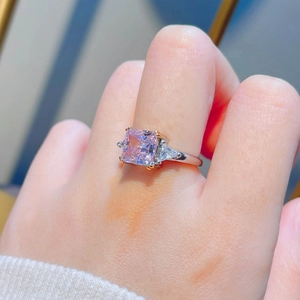 Radiant cut pink diamond ring in silver band with side triangular stones on finger