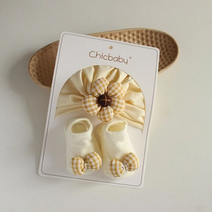 Detail of infant floral headband and checkered bow socks set on white packaging card
