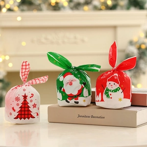 Three Christmas candy gift bags with bunny ear ties featuring Santa, snowman, and tree
