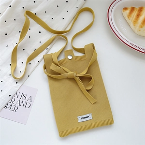Detail of yellow knitted mini crossbody phone bag with bow decoration and metal clasp
