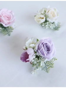 Close-up of handmade faux rose boutonnieres with delicate petals and green leaves