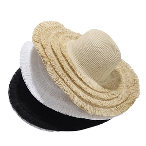 Drei breitkrempige Strohhüte mit Fransenrand in Beige, Weiß und Schwarz im Detail