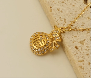 Detail of 18k gold plated fortune bag pendant with zircon inlay on a stone display