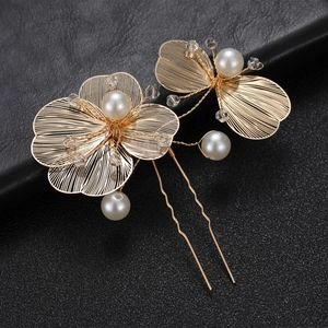 Detail view of a gold floral bridal hair pin with white pearls and crystals