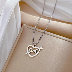 Gros plan d'un collier cœur en argent avec gravure Love et flèche sur une boîte à bijoux