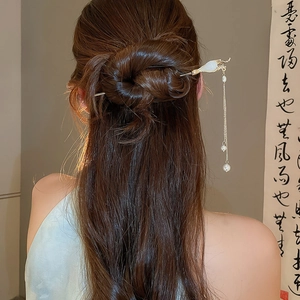 Vue détaillée d'un pic à cheveux chinois avec pompon en perles et design floral doré