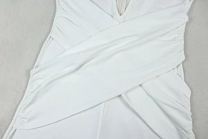 Detailed close-up of the intricate crossover design and ruching on a white jumpsuit