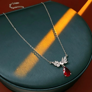 Detailed shot of silver necklace with crystal leaves and a red teardrop pendant on a pedestal