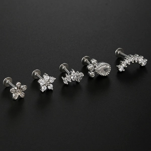 Detailed view of silver stainless steel ear studs with sparkling white gems in various shapes