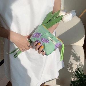 Detail of mint green makeup bag with purple tulip embroidery and yellow zipper