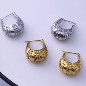 Detailed close-up of chunky gold and silver textured hoops with ribbed industrial pattern