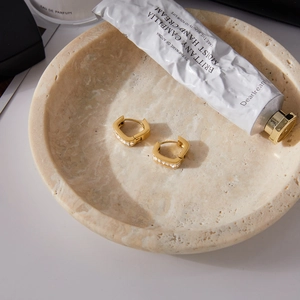 Gros plan de boucles d'oreilles dorées en U avec cristaux sur un plateau en pierre