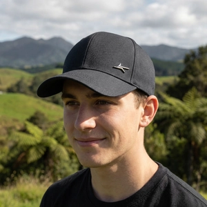 Classic black baseball cap with silver metal logo shown on a model in nature