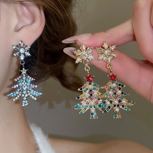 Close-up of Christmas tree earrings with colorful crystals, pearls and snowflake studs