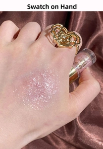 Sparkling pink liquid eyeshadow swatch on hand with silver glitter over satin background