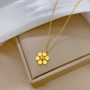 Detail shot of a golden flower pendant necklace on a premium beige display stand