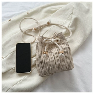 Detail of hand-woven straw bucket bag with white drawstring closure and metal buckle