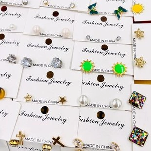 Flat lay of mixed earring sets with butterfly, sun, pearl, and cross elements