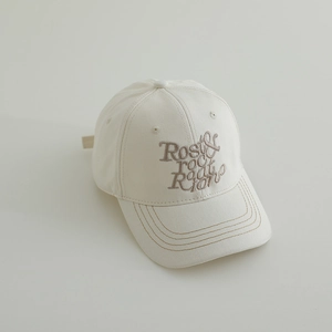 Gros plan d'une casquette en coton crème avec broderie marron et bord surpiqué