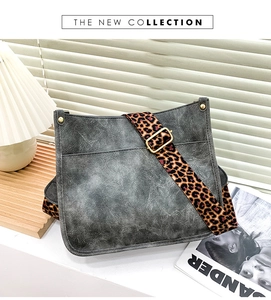 Detail of vintage gray crossbody bag with leopard print strap and golden buckle hardware