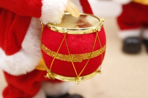 Close-up of electric climbing Santa Claus playing a drum with festive red plush detail