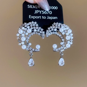 Detailed macro view of silver moon earring with round pearls and a pear-cut zircon pendant