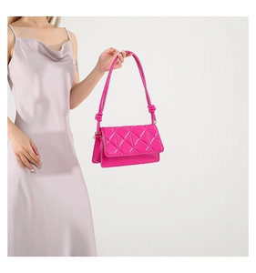 Detail of bright pink crossbody bag featuring geometric quilted pattern and knotted strap