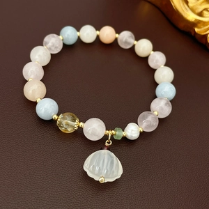 Detail view of natural stone elastic bracelet with freshwater pearl and shell charm