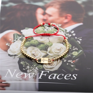 Red string bracelet with gold beads, zircon cross charm on a decorative magazine background
