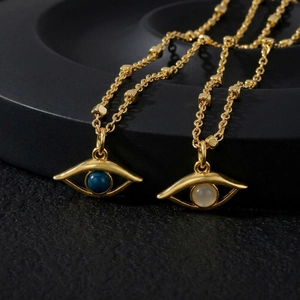 Macro detail of 18K gold plated Evil Eye necklaces with blue and white stone inlays