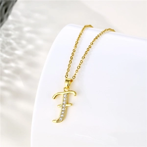 Detailed macro view of an 18K gold letter F pendant with sparkling cubic zirconia stones