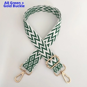 Detail view of a green woven shoulder strap with wavy patterns and golden metal hooks