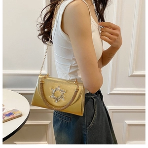 Detail of a chic gold chain crossbody bag with rhinestone sun motif on a model