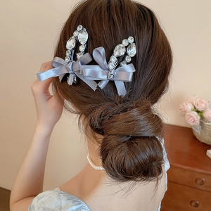 Gros plan de barrettes à nœuds en soie grise et strass sur des cheveux bruns