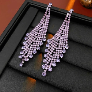 Vue macro détaillée de boucles d'oreilles à pampilles en strass violets dans un coffret