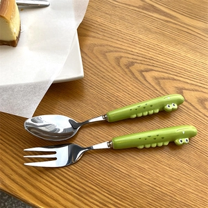 Close-up of kids' stainless steel spoon and fork set with green ceramic crocodile handles