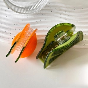Acetate fruit-shaped claw clips in orange and lime designs on white wavy tray