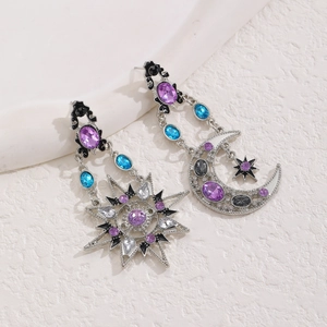 Macro shot of silver sun and moon earrings with purple and blue crystals on stone