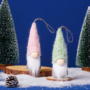 Detail of knitted Christmas gnomes with faux fur beards on wood with snowy blue backdrop