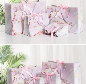 Detailed view of pink marble pattern gift bag with satin ribbon and gold Happy Times text