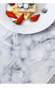 Macro shot of 4 transparent acrylic tablecloth clips on a textured grey placemat