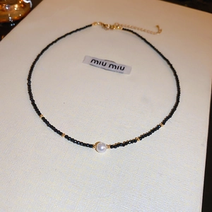 Collier ras de cou en perles noires avec perle blanche centrale et détails dorés chic