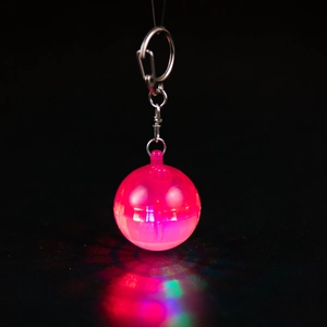 Pink glowing disco ball keychain with silver metal clip on a black background