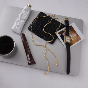Flat lay of 18K gold plated bead necklace, vintage square watch and leather wallet