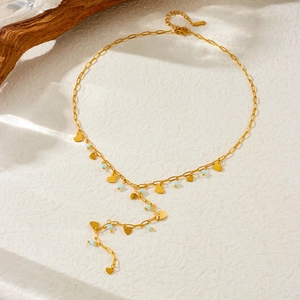 Detail of Y-shaped gold necklace with heart pendants and light blue beads on paper