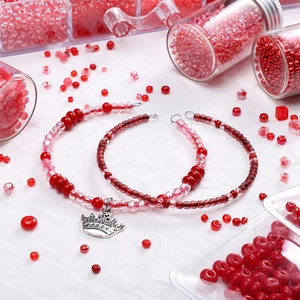 Red glass bead set for DIY jewelry with silver crown pendant on white background