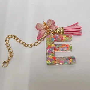 Detail of initial E keychain with heart glitter, pink butterfly charm and golden clasp
