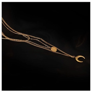 Detail view of a multi-layer gold necklace with crescent and oval pendants on black background
