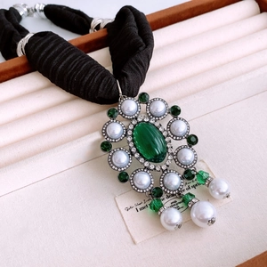 Close-up of Baroque vintage emerald green stone pendant with elegant pearl accents