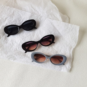 Retro oval cat eye sunglasses in black, brown, and grey frames on a textured white background